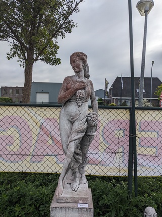 Tuinbeeld vrouw met druiven op sokkel gepatineerd