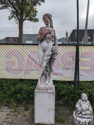 Tuinbeeld vrouw met druiven op sokkel gepatineerd